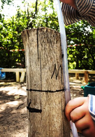 Maßnehmen mit Hilfe eines Wasserschlauches beim Bau des grünen Klassenzimmers.